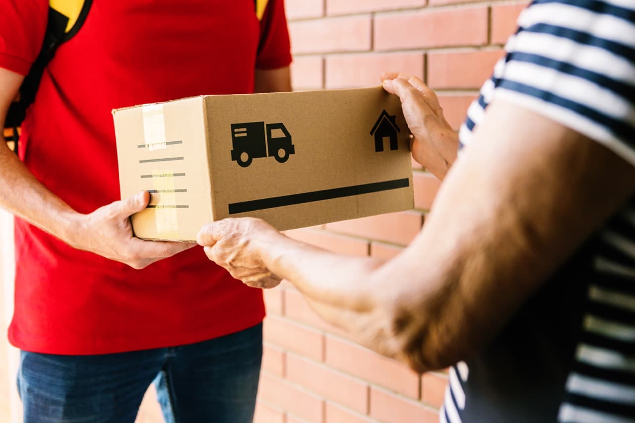 Postman in red uniform delivering package to costumer - Senior woman receiving a parcel at the door of home - Delivery service concept Home Interior Shop
